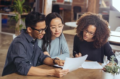 A group of people discuss paperwork